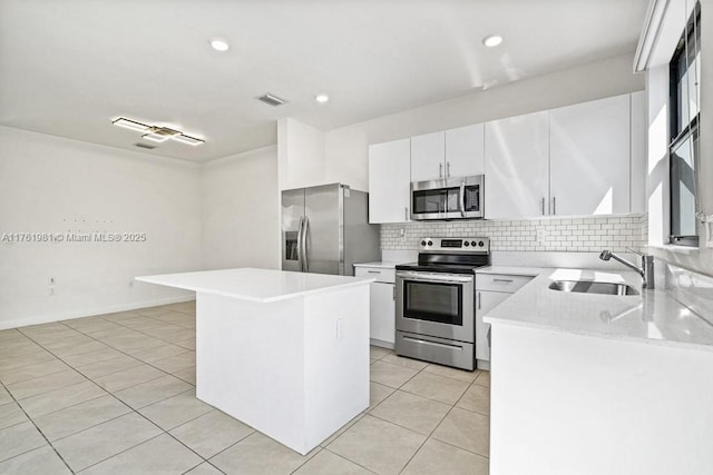 kitchen featuring a kitchen island, light countertops, decorative backsplash, appliances with stainless steel finishes, and a sink