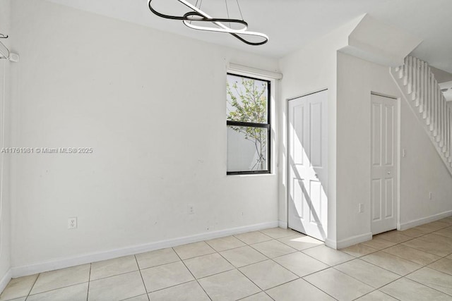 spare room with light tile patterned flooring and baseboards