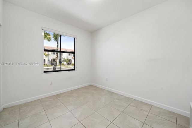 empty room with light tile patterned floors and baseboards