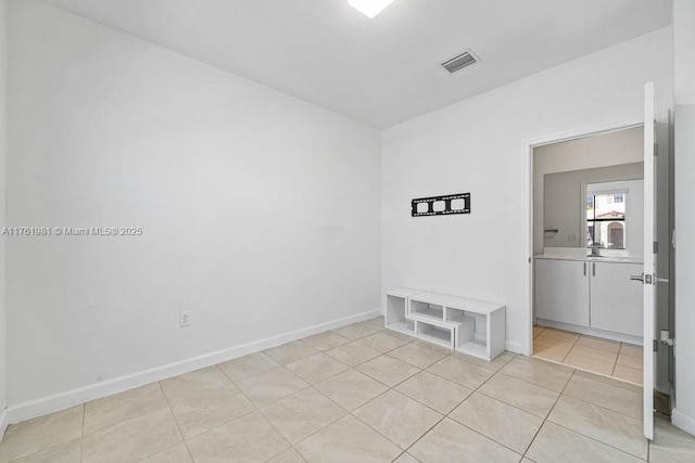 spare room featuring light tile patterned floors, visible vents, and baseboards