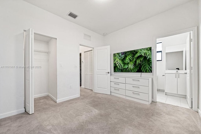 unfurnished bedroom with a spacious closet, visible vents, and light carpet