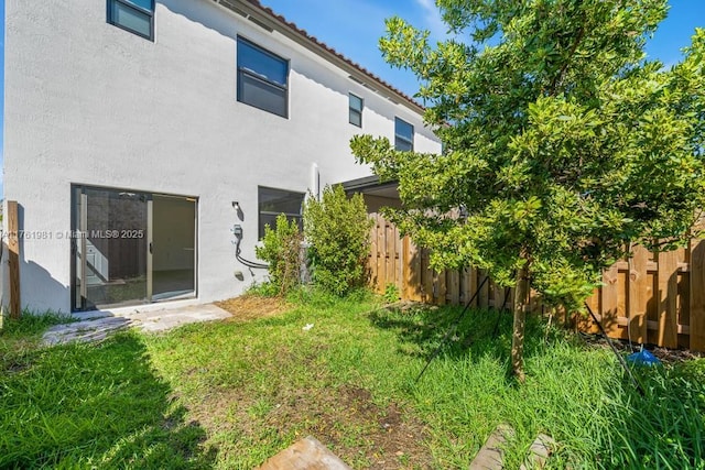 rear view of property with fence, a lawn, and stucco siding