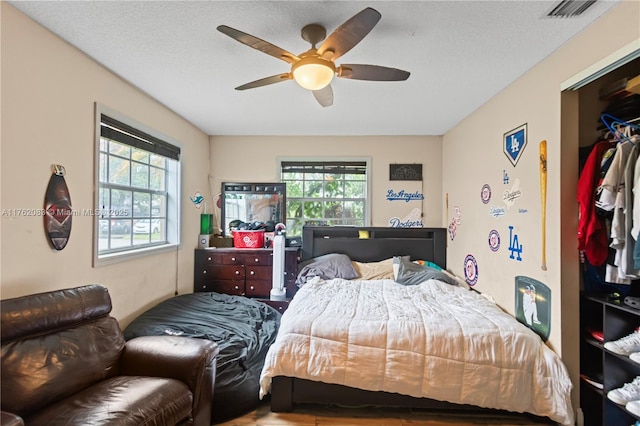 bedroom with visible vents, wood finished floors, ceiling fan, and multiple windows