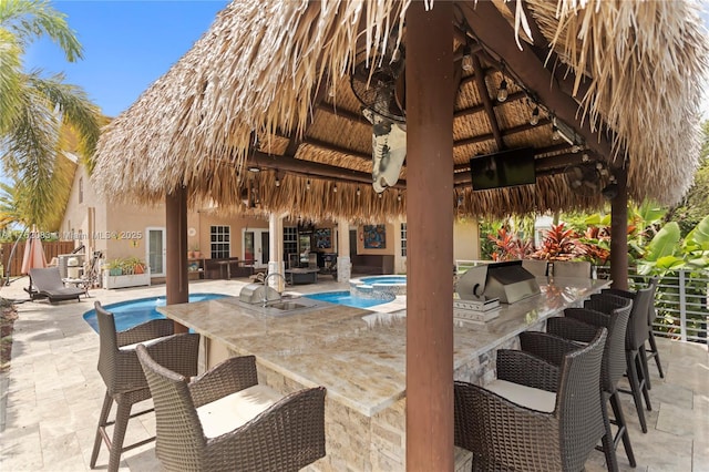 view of pool featuring a gazebo, outdoor wet bar, exterior kitchen, and fence
