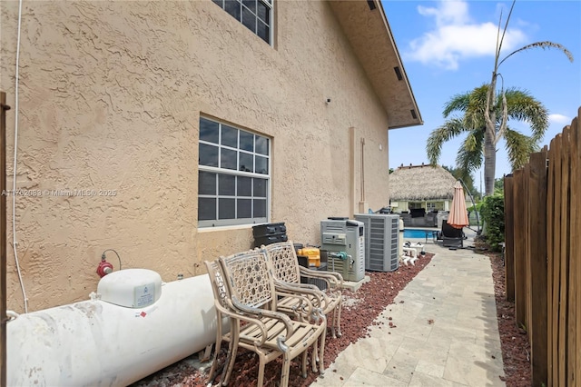 view of home's exterior with a patio area, central AC, stucco siding, and fence