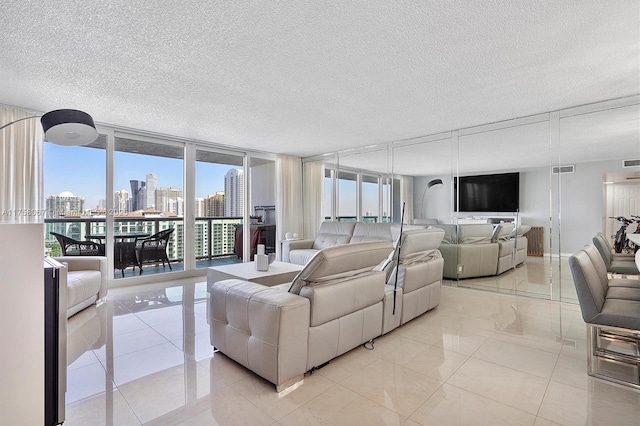 living area featuring visible vents, a city view, a wall of windows, light tile patterned floors, and a textured ceiling