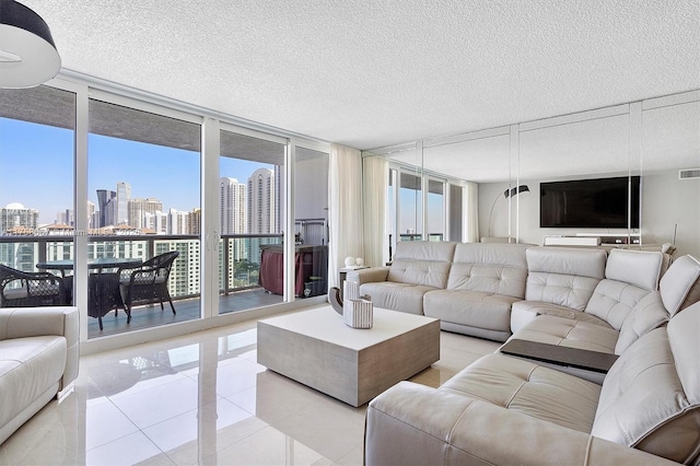 living room featuring visible vents, light tile patterned flooring, floor to ceiling windows, a textured ceiling, and a city view