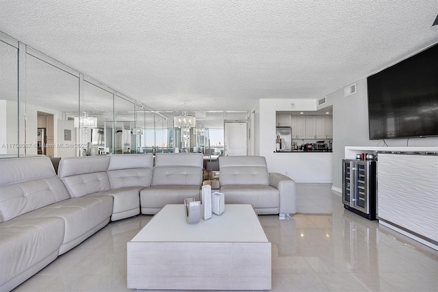 living area featuring visible vents, a notable chandelier, beverage cooler, and a textured ceiling