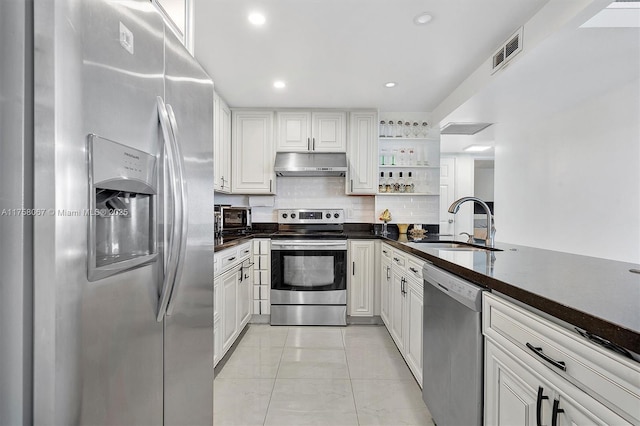 kitchen featuring under cabinet range hood, a sink, dark countertops, appliances with stainless steel finishes, and white cabinets