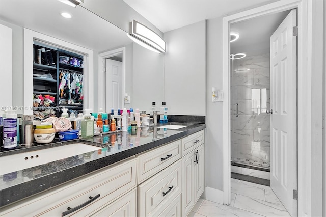 bathroom featuring a marble finish shower, double vanity, a sink, a walk in closet, and marble finish floor