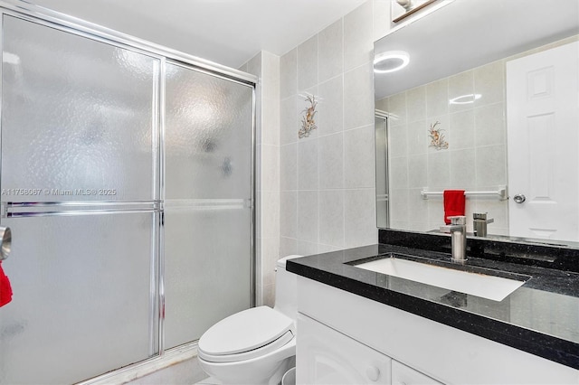 bathroom featuring toilet, tile walls, a shower stall, decorative backsplash, and vanity