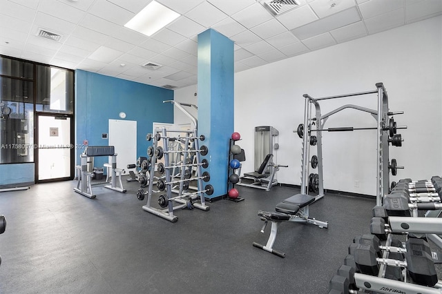 exercise room with a drop ceiling, visible vents, and baseboards