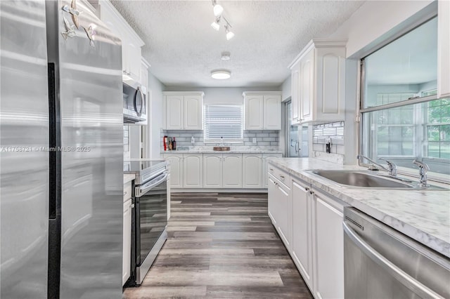 kitchen with a sink, a wealth of natural light, appliances with stainless steel finishes, and white cabinets