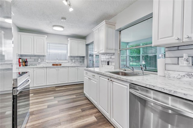 kitchen featuring a sink, backsplash, light wood-style floors, appliances with stainless steel finishes, and white cabinets