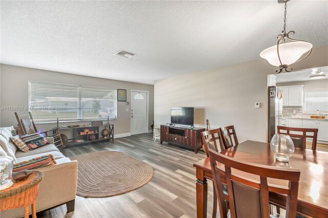 living area featuring visible vents, a textured ceiling, and wood finished floors