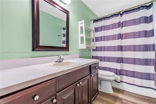 bathroom with vanity, a shower with shower curtain, toilet, and wood finished floors