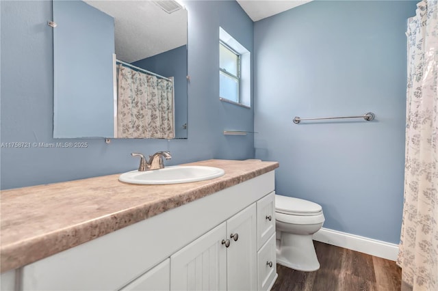 bathroom featuring vanity, wood finished floors, visible vents, baseboards, and toilet