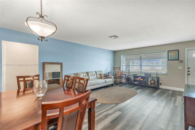 dining room with visible vents, a textured ceiling, baseboards, and wood finished floors