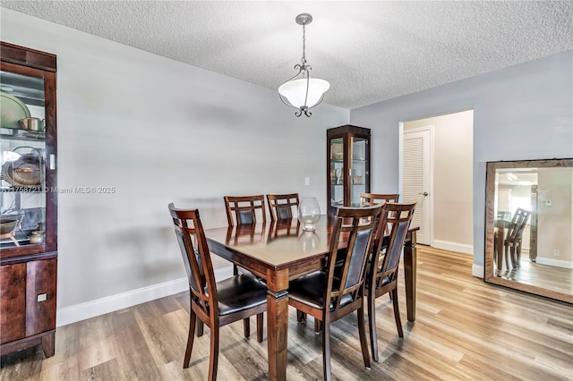 dining room with baseboards, a textured ceiling, and light wood finished floors