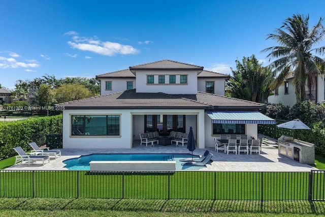 back of house featuring fence, an outdoor kitchen, a yard, stucco siding, and a patio area