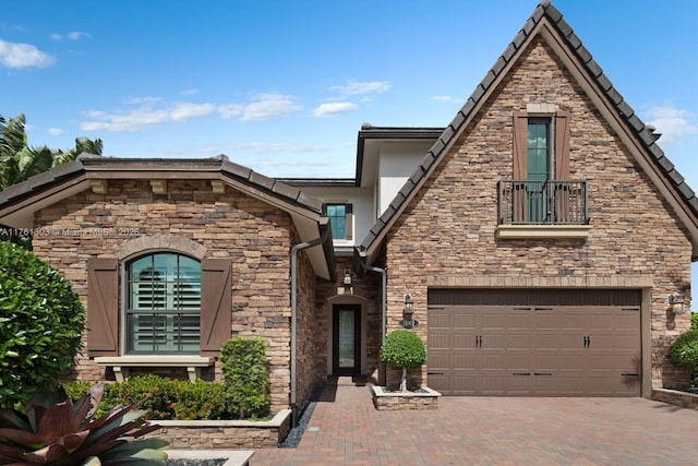 view of front of home with decorative driveway, stone siding, and a garage