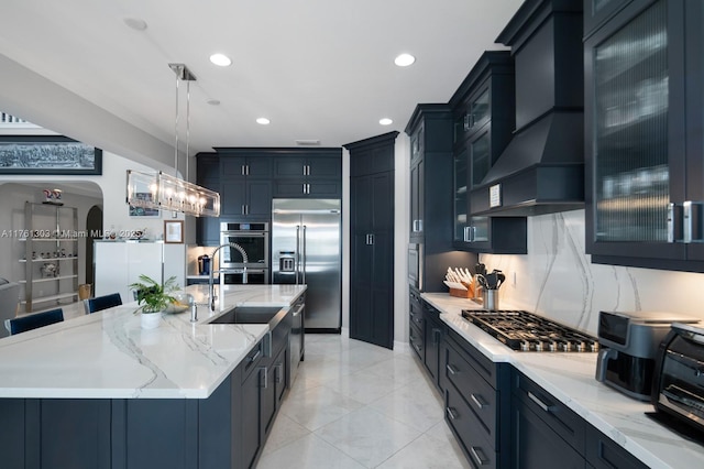 kitchen featuring light stone countertops, arched walkways, custom range hood, glass insert cabinets, and appliances with stainless steel finishes