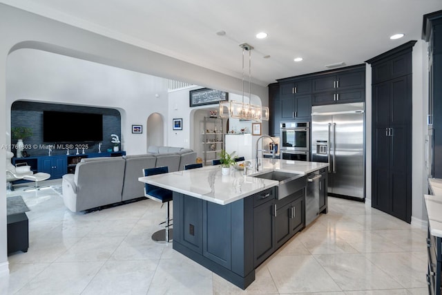 kitchen with pendant lighting, a breakfast bar area, arched walkways, stainless steel appliances, and a sink