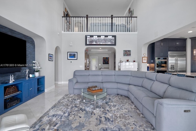 living area featuring a towering ceiling, arched walkways, and marble finish floor