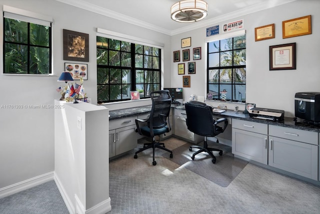 carpeted office featuring a wealth of natural light, built in desk, crown molding, and baseboards