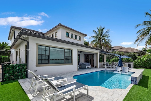 rear view of house with a patio area, an outdoor pool, and stucco siding