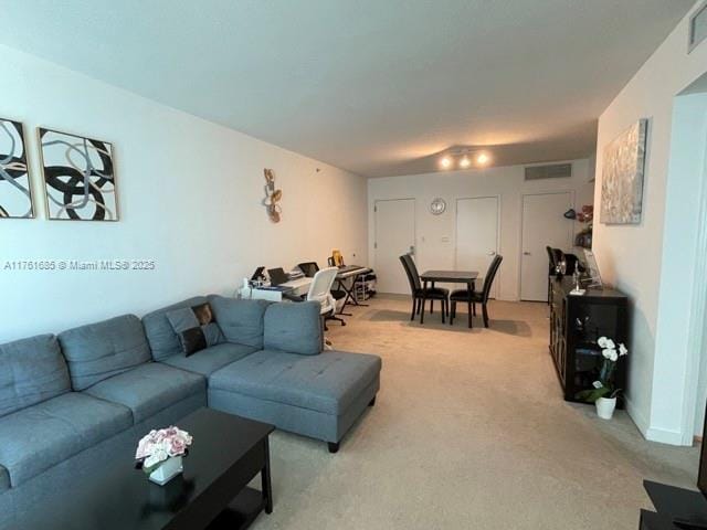 living area with visible vents and light carpet