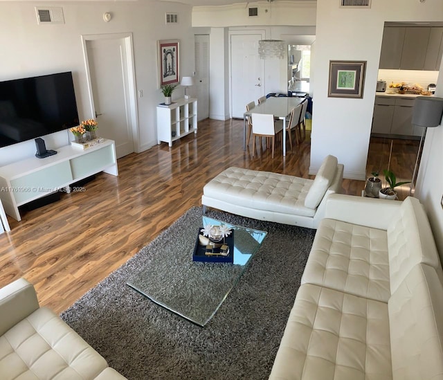 living area featuring visible vents and wood finished floors