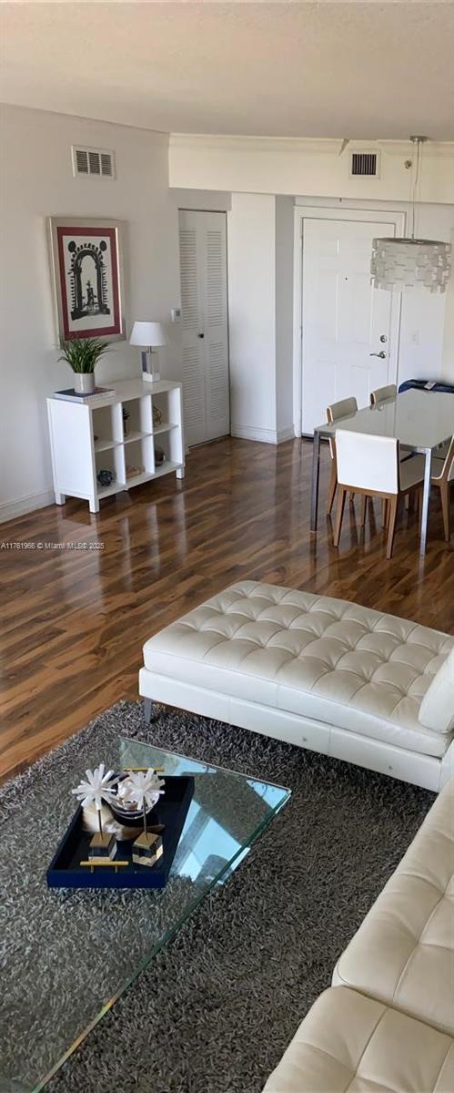 living area featuring visible vents and wood finished floors