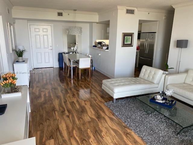 living room with visible vents, wood finished floors, and ornamental molding