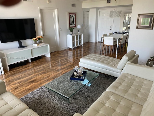 living area with visible vents, baseboards, and wood finished floors