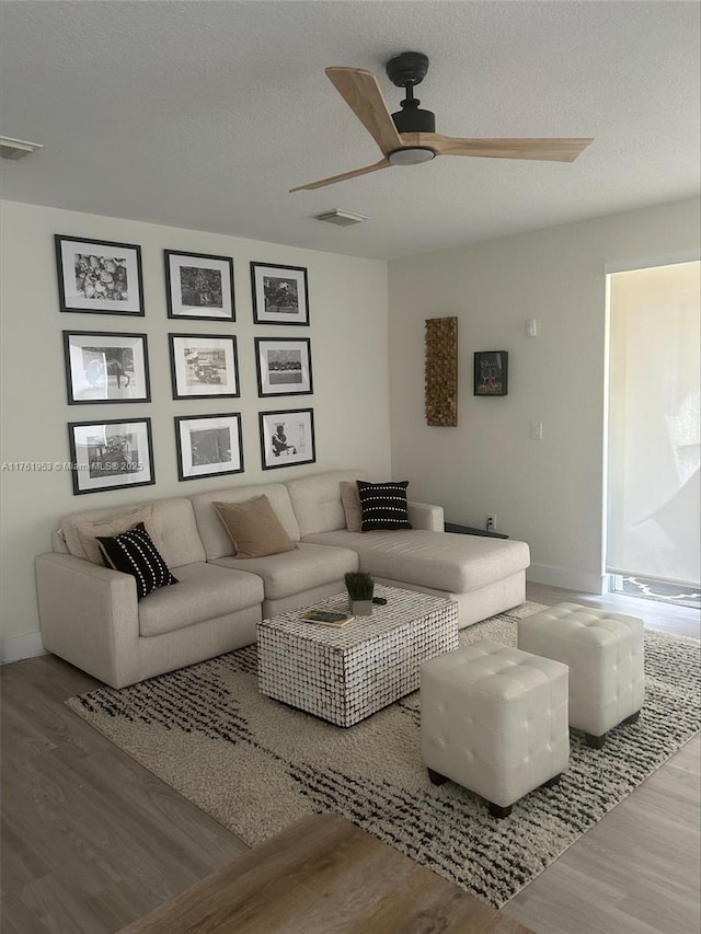 living room with visible vents, baseboards, a ceiling fan, and wood finished floors