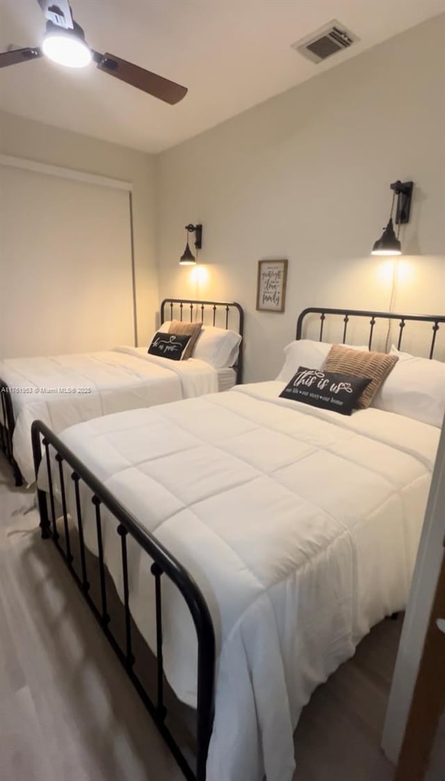 bedroom with a ceiling fan, wood finished floors, and visible vents