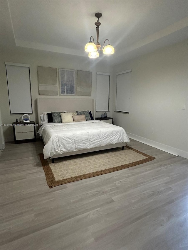 bedroom featuring a chandelier, baseboards, and wood finished floors