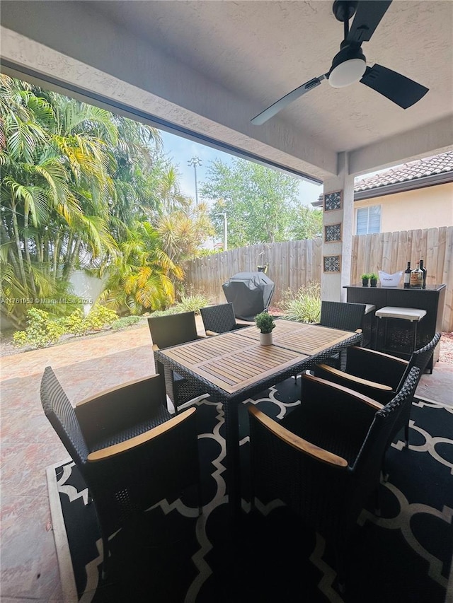 view of patio with area for grilling, outdoor dining space, a ceiling fan, and fence
