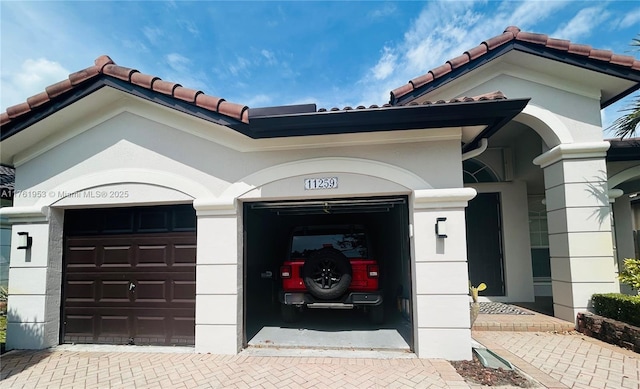 exterior space with a tiled roof, decorative driveway, and a garage