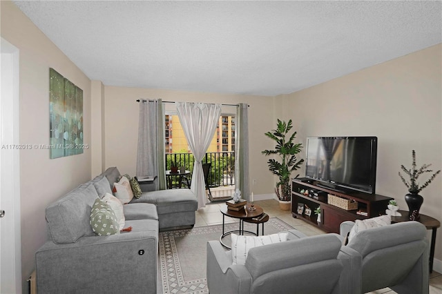 living area with light tile patterned flooring, a textured ceiling, and baseboards