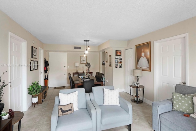 living room featuring light tile patterned floors, visible vents, and a textured ceiling