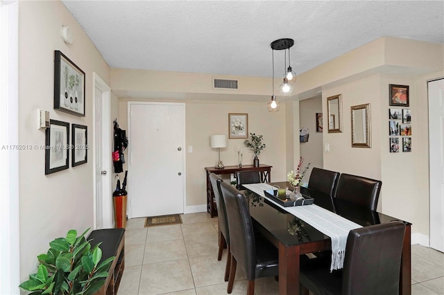 dining room with light tile patterned floors, visible vents, baseboards, and a textured ceiling