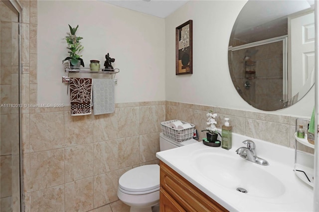 bathroom with toilet, a stall shower, tile walls, wainscoting, and vanity