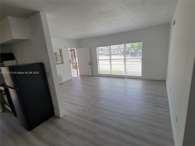 unfurnished living room with wood finished floors, baseboards, and a wealth of natural light