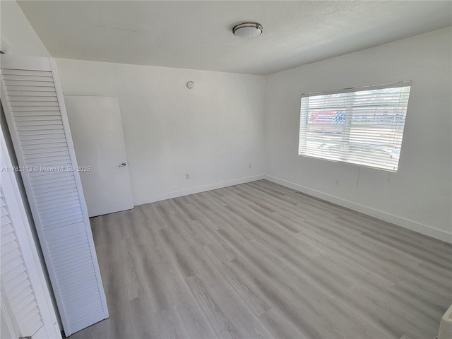 spare room with light wood-type flooring and baseboards