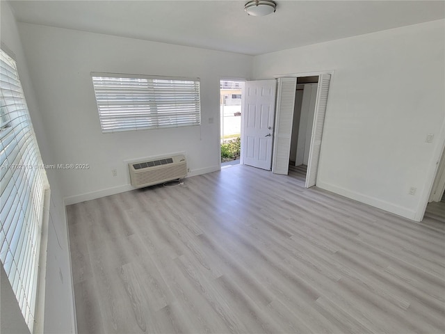 spare room featuring an AC wall unit, wood finished floors, and baseboards