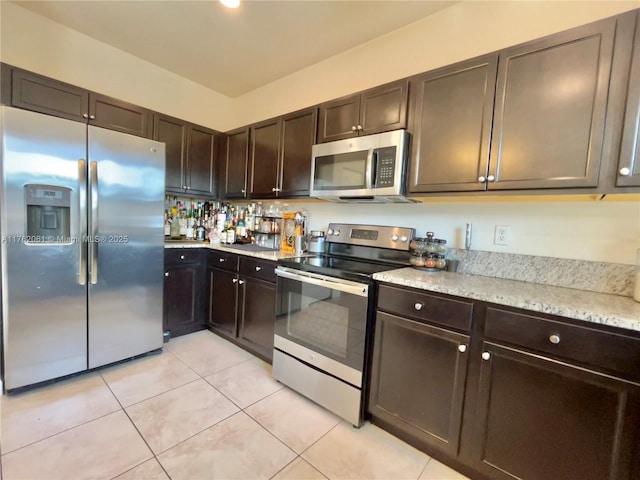 kitchen with light stone counters, dark brown cabinets, light tile patterned floors, and stainless steel appliances