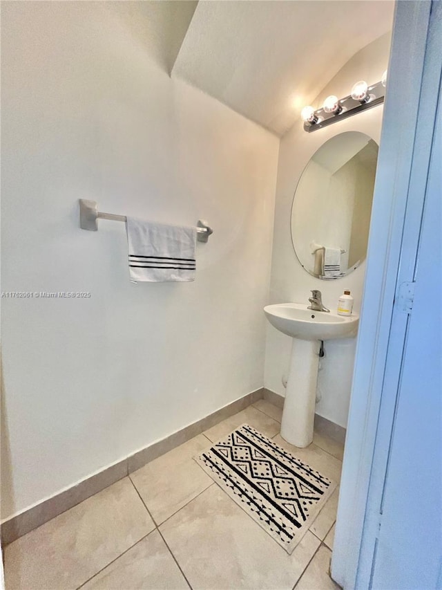 bathroom with tile patterned floors, baseboards, and lofted ceiling