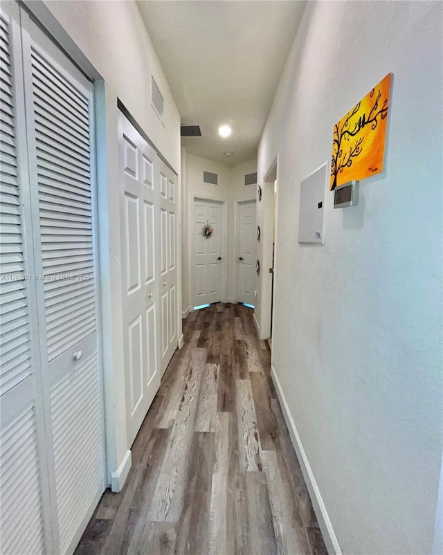 corridor featuring visible vents, baseboards, and wood finished floors